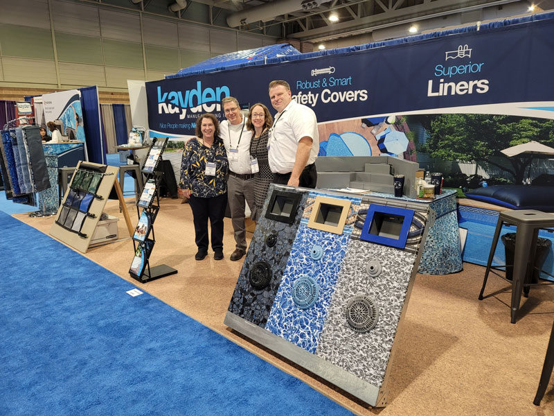 A picture of the founders and leadership team of Kayden Manufacturing at a trade show with pool tiling samples
