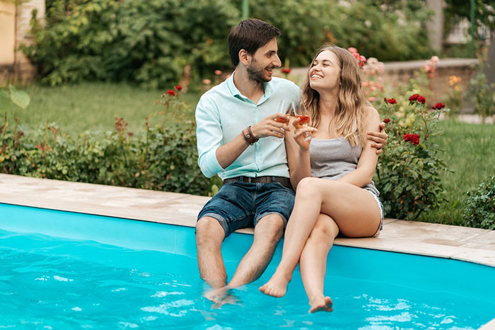 A picture of two happy homeowners enjoying their pool on the edge of a pool
