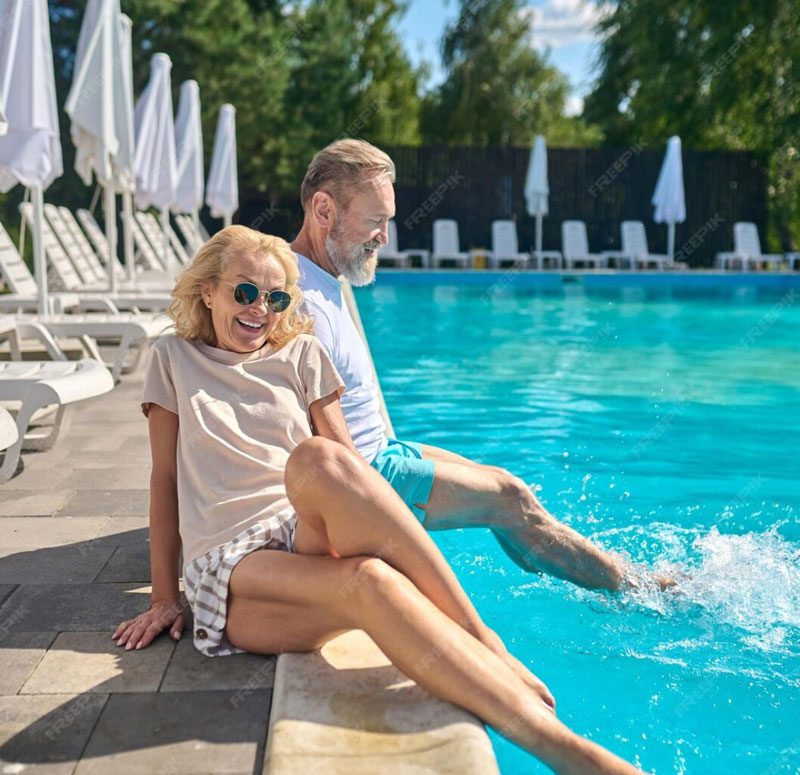 A picture of a man and a woman dipping their feet in the pool at the edge of a pool