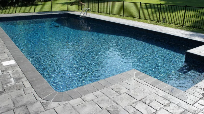 A blue pool liner with grey stones around the perimeter of the pool